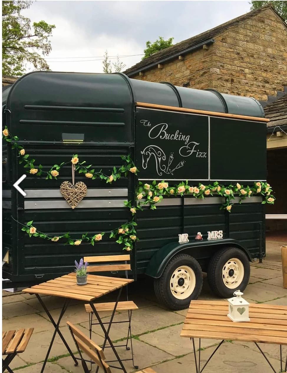 Dark green horse trailer bar named "The Bucking Fizz" decorated with roses and wicker heart.