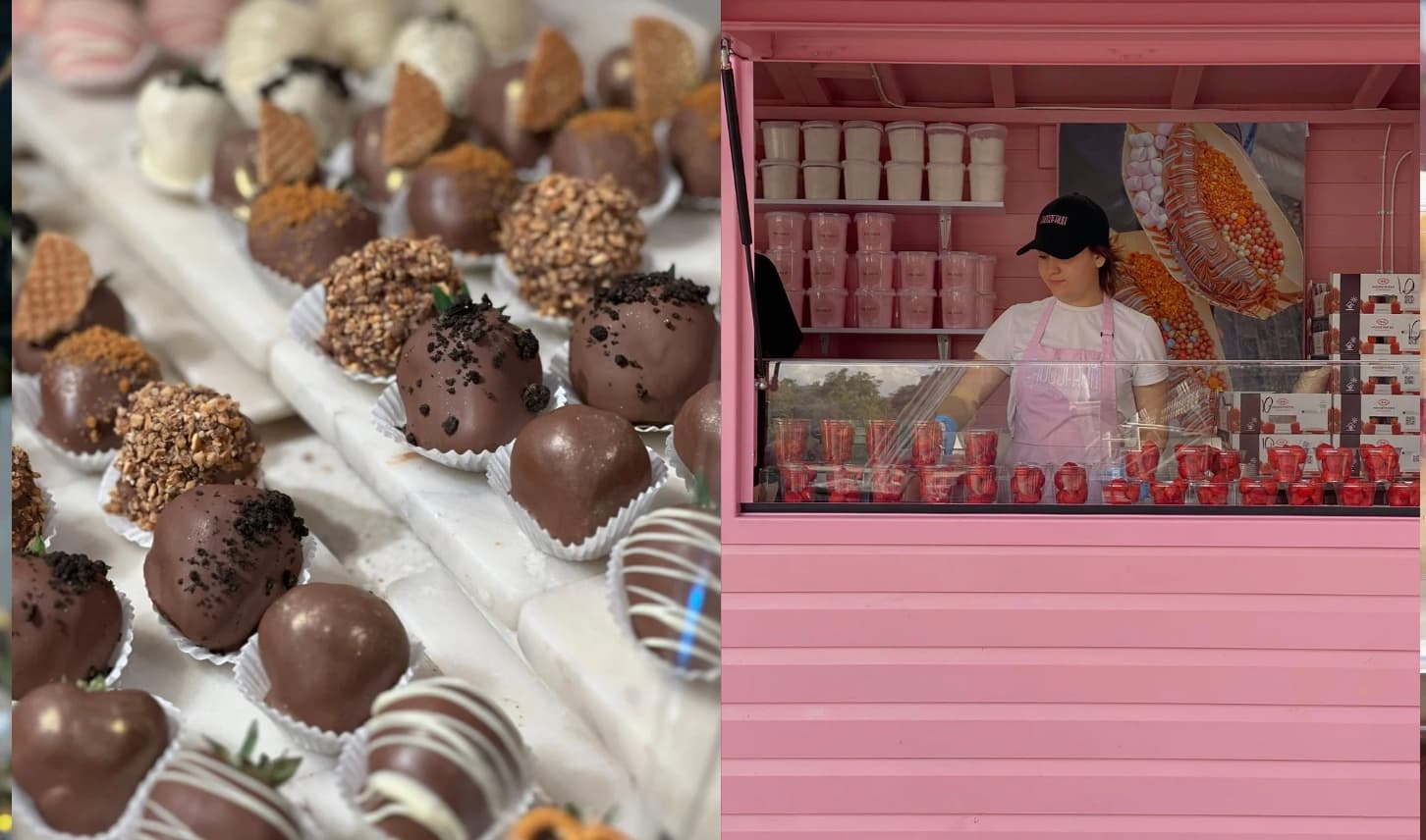 Assorted chocolate-covered strawberries displayed beside a woman working inside a bright pink food stall.